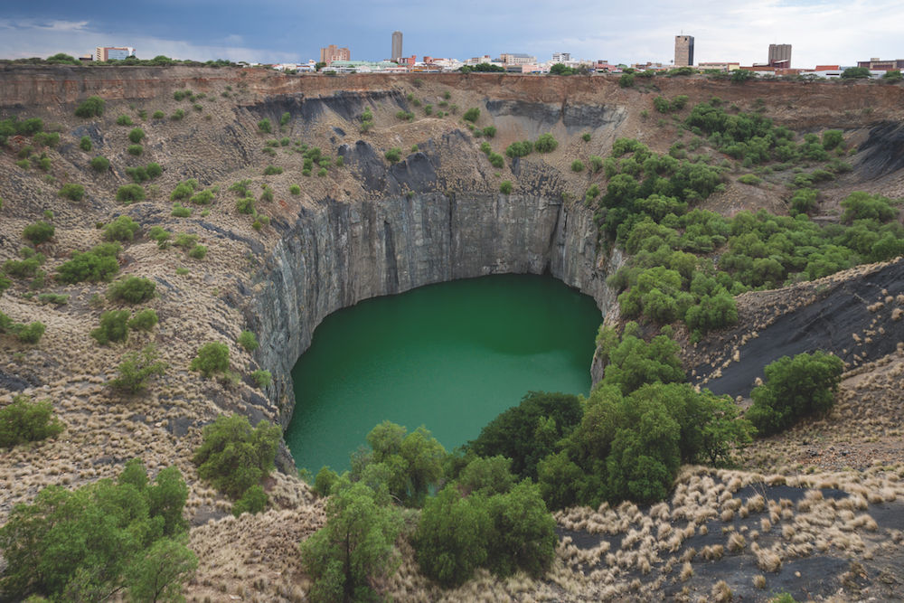 Ein See und seine Geschichte: „Das Große Loch“ bei Kimberley in Südafrika, gefüllt mit Grundwasser, ist durch Diamantenabbau entstanden. Erst mit der Stadtsilhouette im Hintergrund entfaltet das Bild seine Wirkung. Foto: Siegfried Layda