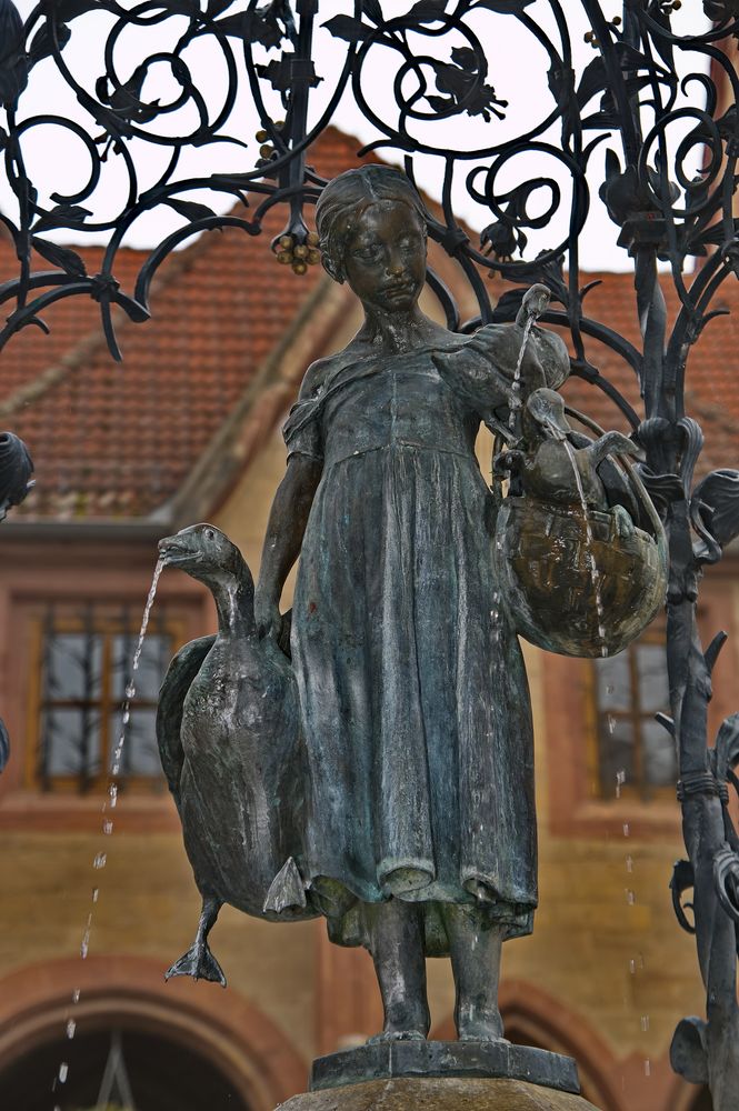 Skulptur einer abstrakten Figur aus Metall, die ein Mädchen mit Gänsen zeigt.
